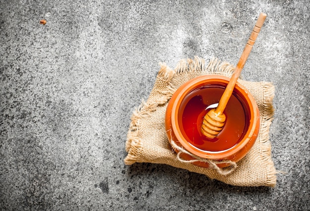 Fresh honey in a clay pot with a wooden spoon