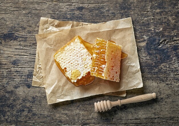 Fresh honey comb pieces on rustic wooden kitchen table, top view