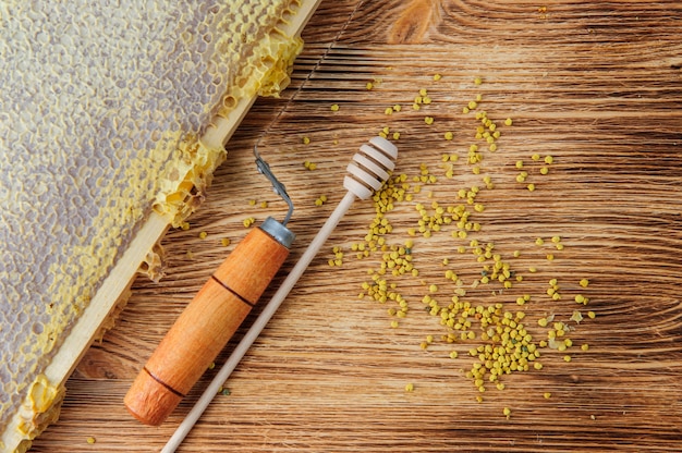 Fresh honey in the comb and the tools of the beekeeper on a brown wood table. 