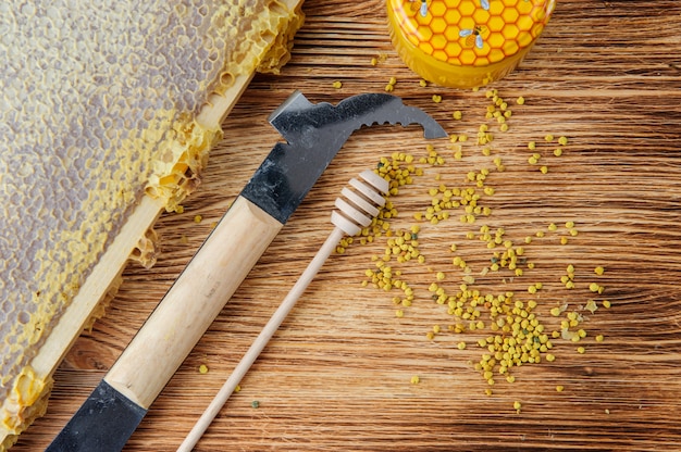 Fresh honey in the comb and the tools of the beekeeper on a brown wood table. 