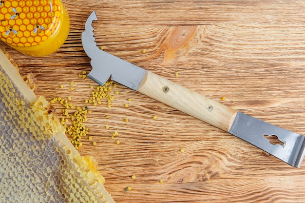 Fresh honey in the comb and the tools of the beekeeper on a brown wood table. 