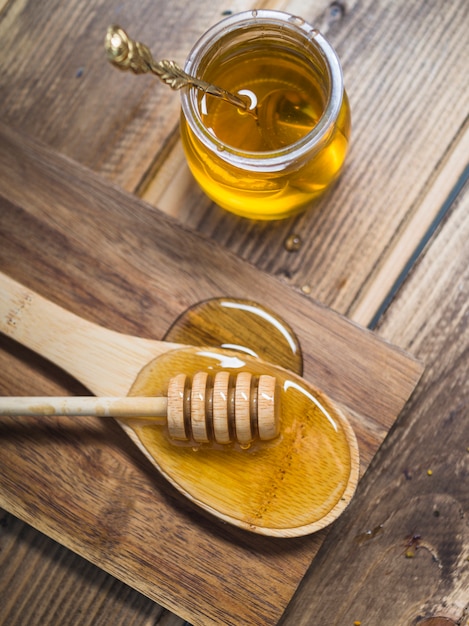 Foto merlo acquaiolo fresco del miele sul cucchiaio e sul vaso di legno con il cucchiaio