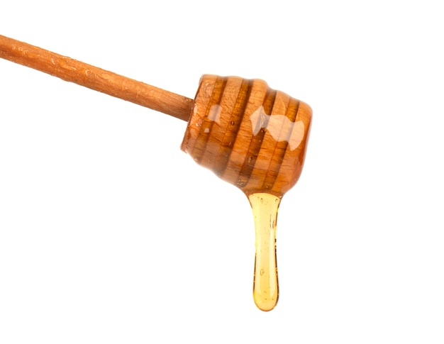 Fresh honey dripping from a honey dipper isolated on white , bee products by organic natural ingredients concept