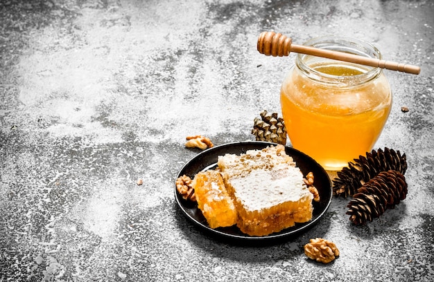 Fresh honey in a jar and honeycomb with nuts. On rustic background.