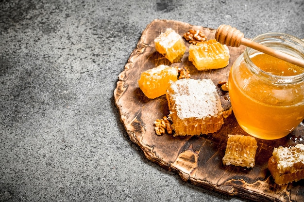 Photo fresh honey in a jar and honeycomb with nuts on rustic table.