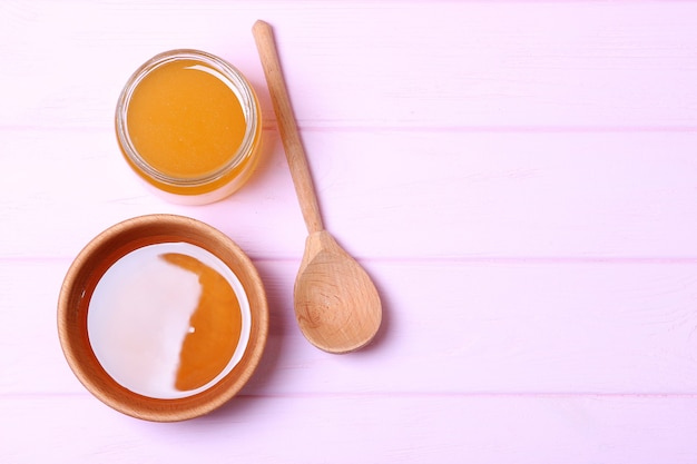 Fresh honey on the table closeup on a colored background