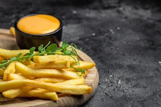 Fresh hot french fries with with cheese sauce on a dark concrete background Restaurant menu dieting cookbook recipe top view