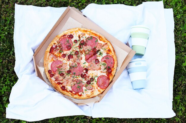 Fresh hot pizza with tomato sauce and bacon at a picnic