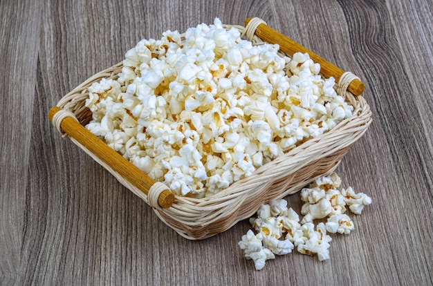 Photo fresh hot popcorn in the basket on wood background