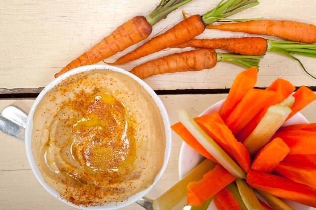 Fresh hummus dip with raw carrot and celery