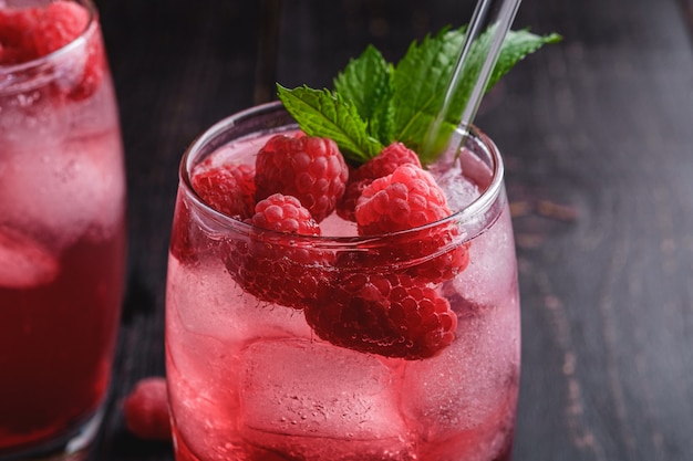 Photo fresh ice cold berry juice drink with mint, summer raspberry lemonade in glass with straws on dark