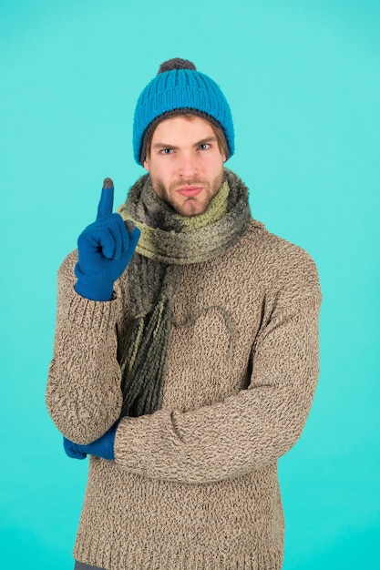 Fresh idea. Man handsome unshaven guy wear winter accessories on blue background. Shopping concept. Emotional expression. Winter season sale. Hipster knitted winter hat scarf and gloves. Finger up.