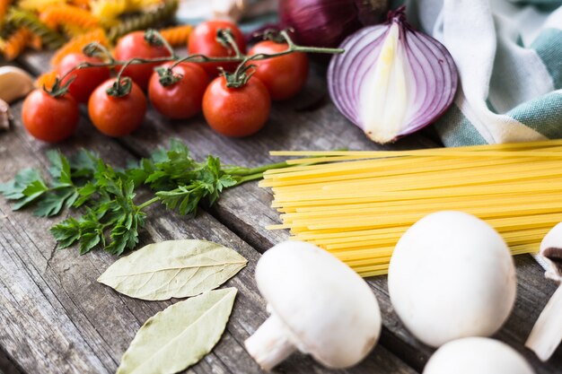 Fresh ingredients for cooking pasta, tomato and spices over wooden table with copy space