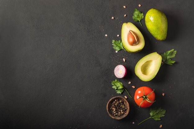 Fresh  ingredients for guacamole avocado tomatored onion cilantro on a black background