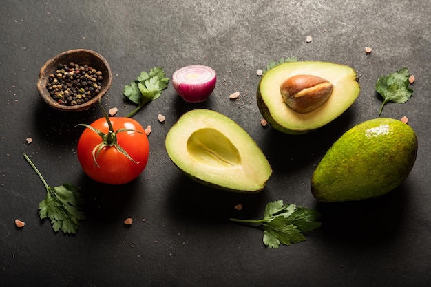 Fresh  ingredients for guacamole avocado tomatored onion cilantro on a black background