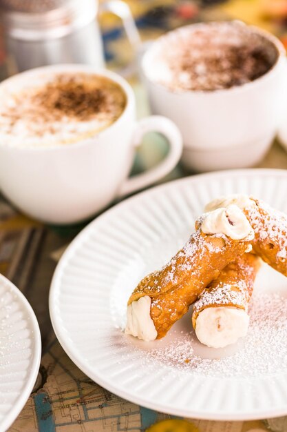 Fresh Italian cannoli with coffee on the table.