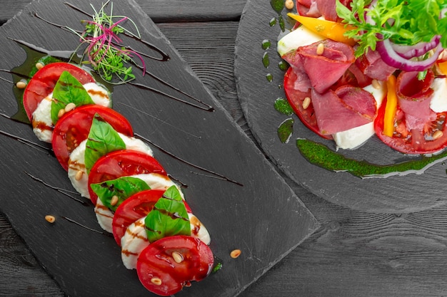 Fresh italian caprese salad with mozzarella and tomatoes on dark plate