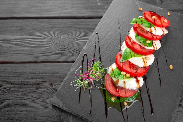 Fresh italian caprese salad with mozzarella and tomatoes on dark plate