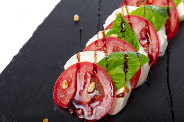 Fresh italian caprese salad with mozzarella and tomatoes on dark plate