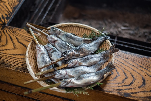 꼬치 대나무 지팡이로 일본 전통 바베큐를 준비하는 신선한 iwana 물고기