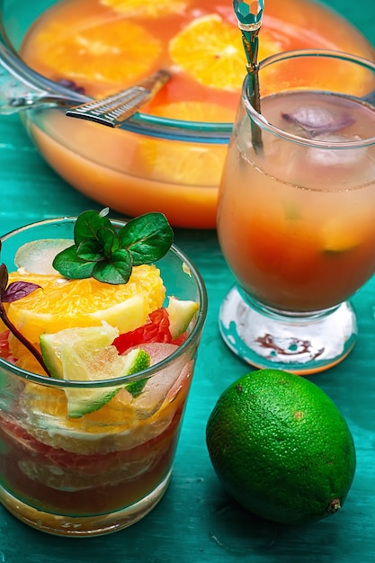 Fresh juice from oranges, kiwi and grapefruit on turquoise wooden background.