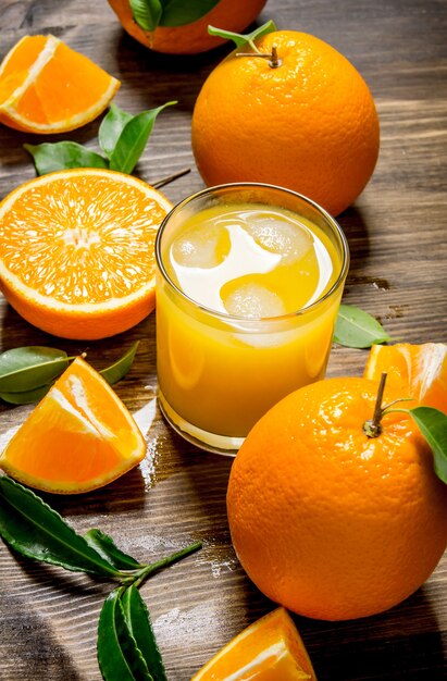 Fresh juice in glass and oranges slices with leaves