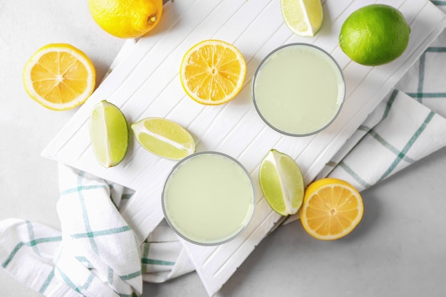 Fresh juice in glasses and sliced citrus fruits on table