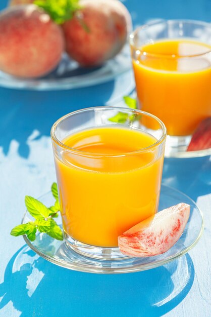 Fresh juice and peaches on a blue table