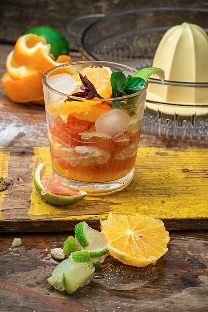 Fresh juice of tropical citrus fruits on wooden background.