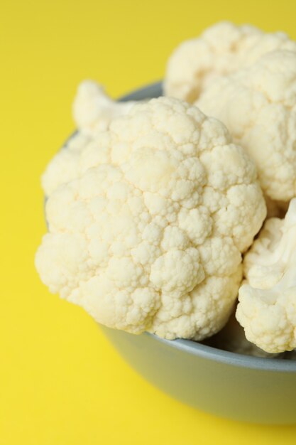 Fresh juicy cauliflower slices in bowl on yellow background