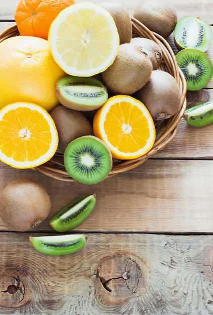 Fresh juicy citrus fruits in a basket on  wooden surface