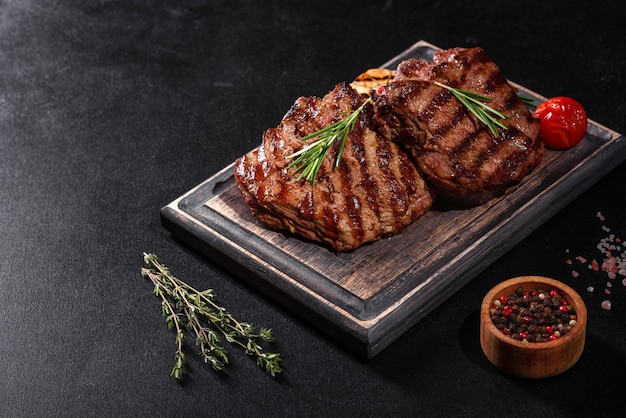 Photo fresh juicy delicious beef steak on black board. meat dish with spices and herbs