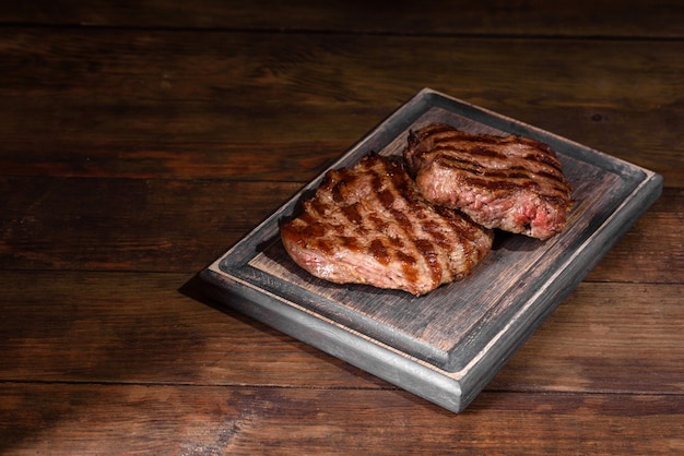 나무 테이블에 신선한 육즙 맛있는 쇠고기 스테이크. 향신료와 허브와 고기 요리