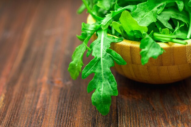 Fresh juicy leaves of arugula on a brown wooden table.