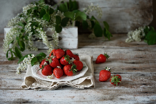 Fragole organiche succose fresche su una vecchia tabella strutturata di legno