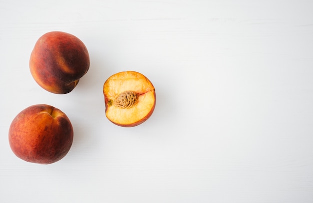 Fresh juicy peach on white wooden table.