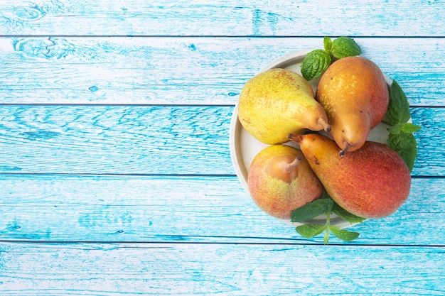 Conferenza succosa fresca delle pere su fondo luminoso di legno blu. raccolta autunnale di frutti maturi. copia spazio