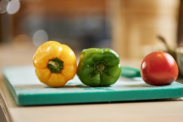 Fresh juicy peppers and tomato on top of kitchen board