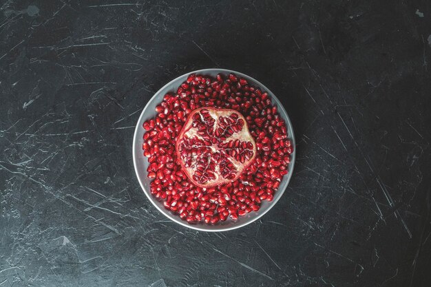 Photo fresh juicy pomegranate whole and cut on a black vintage background top view horizontal with copy space