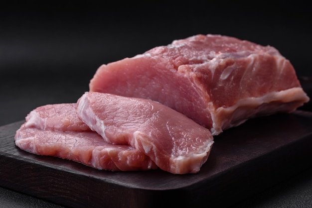Fresh juicy pork on a wooden cutting board with spices and salt
