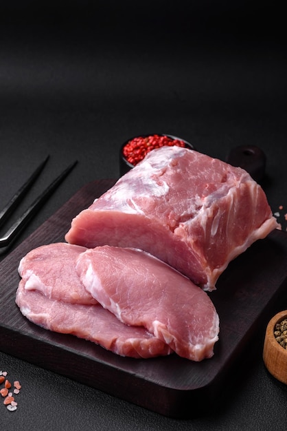 Fresh juicy pork on a wooden cutting board with spices and salt