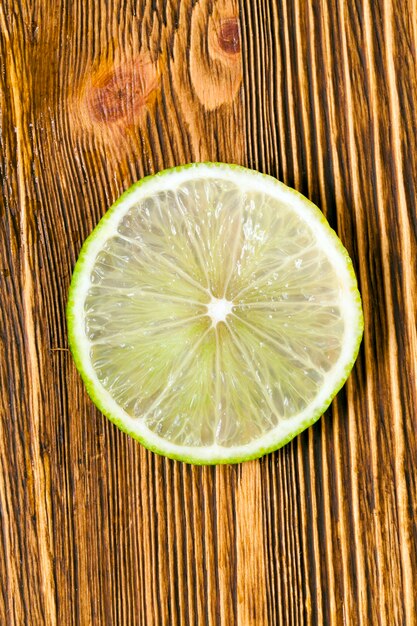Fresh juicy slice of green lime, photographed close-up on an old wooden table.