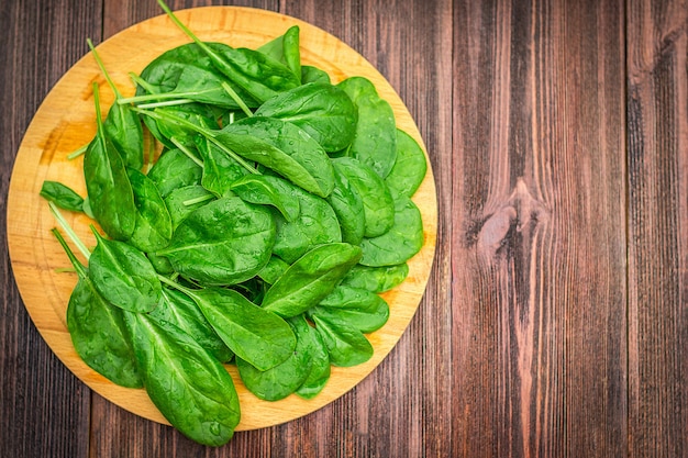 新鮮なジューシーなほうれん草は木製の茶色のテーブルに残します。天然物、野菜、健康食品