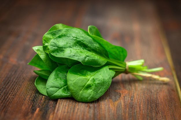 Fresh juicy spinach leaves on a wooden brown table. Natural products, greens, healthy food