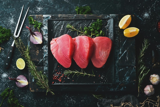 Photo fresh juicy tuna steak on a black stone plate on a dark background top view