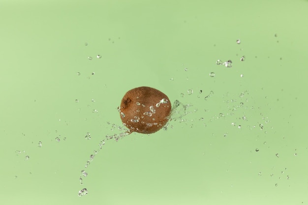 Fresh kiwi on green background with a water splash