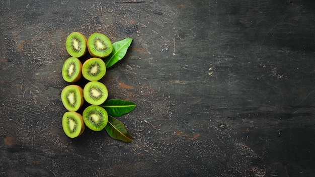 Fresh kiwi and green leaves on the table. Rustic style. Fruits. Top view. Free space for text.