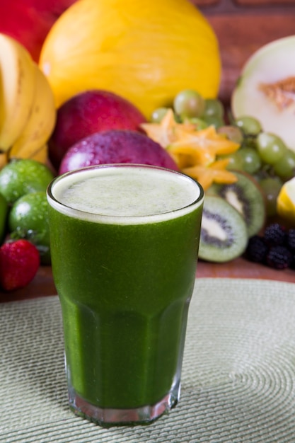 fresh kiwi juice with fruit in the background.