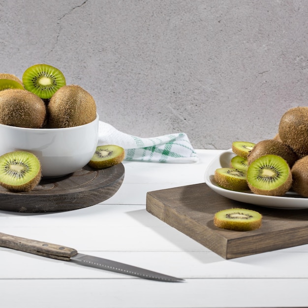 Fresh kiwi and slices on white plate on light background Selective focus Square format