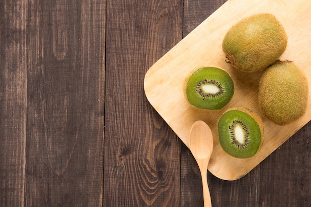 Fresh kiwis fruit and spoon on wooden board.